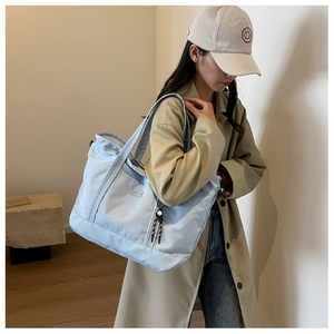 Close-up of a large light blue travel tote bag featuring front pocket and top handles