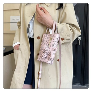 Détail d'un petit sac bandoulière rose imprimé ours avec pendentif en peluche doux