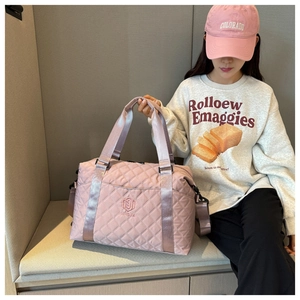 Close-up of pink quilted oxford fabric and embroidered logo on large travel bag