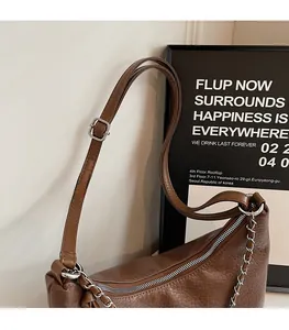 Detail of brown litchi pattern leather tote bag with adjustable strap and metal chain
