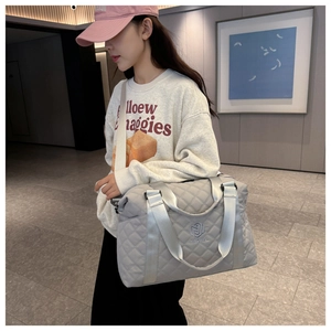 Detailed view of light gray quilted travel bag with NINGJIA logo and wide shoulder strap