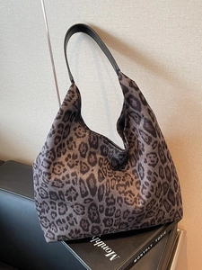 Sac fourre-tout léopard rétro avec bandoulière en cuir noir sur un canapé chic