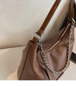 Detail of brown pebbled leather bag featuring high-quality silver chain and hardware accents
