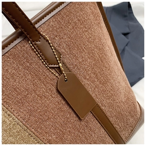 Detail of the brown textured fabric and faux leather stitching on the tote bag