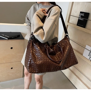 Detail of dark brown leather woven bag with Intrecciato craftsmanship and canvas strap