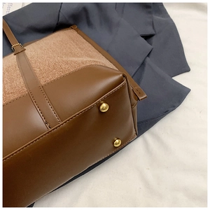 Detailed macro of vintage tote bag base with gold metal feet and dark brown leather trim