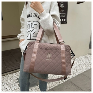 Detailed view of the large pink quilted nylon travel bag with branding in outdoor setting