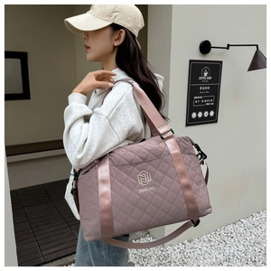 Macro view of mauve quilted nylon travel bag with crossbody strap and embroidered logo