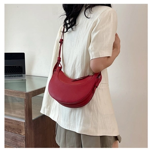 Dettaglio di una borsa a mezzaluna in pelle rossa indossata da una modella in stile casual