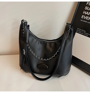 Close-up of black retro textured crescent bag with silver chain and leather strap