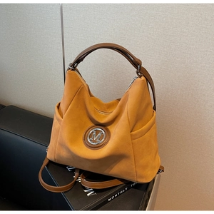 Detail of ginger suede hobo bag featuring silver M logo and functional side pockets