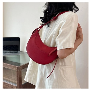 Vista laterale di una borsa a mezzaluna rosso scuro con nodo indossata