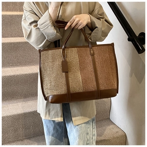 Detail of large contrast tote bag featuring canvas texture and brown leather trim accents