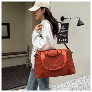 Detail shot of orange quilted oxford travel bag with embroidery and wide shoulder strap