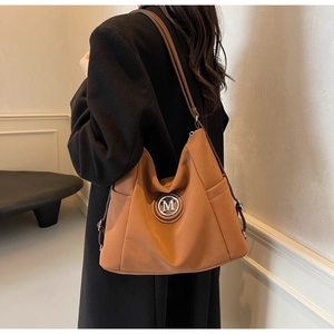 Detail of caramel tote bag with metallic M logo and adjustable slim shoulder strap
