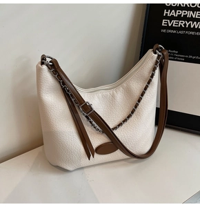 Detail of hobo bag with beige lychee texture, brown leather strap and silver chain