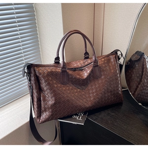 Macro detail of dark brown woven leather travel bag with dual handles and woven strap