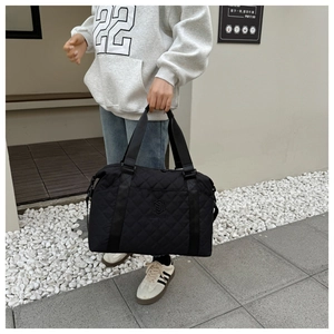 Detail of black quilted travel bag with diamond stitching and adjustable shoulder strap
