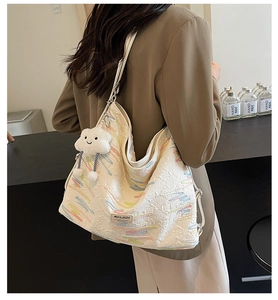 Close-up of beige canvas tote bag with colorful embroidery and white cloud pendant