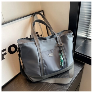 Detail view of large capacity blue nylon tote bag with shoulder strap and woven accessory
