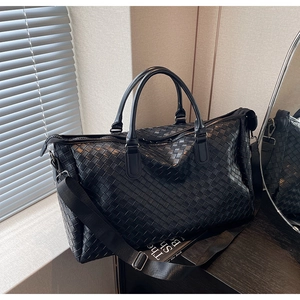 Detail of black woven texture large travel tote bag with leather straps and top zipper