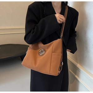 Detail of the caramel nylon tote bag featuring a metallic M logo and side pocket