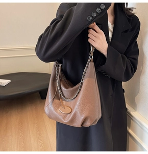 Close-up of brown litchi leather hobo bag with silver chain strap on professional attire