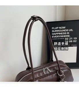 Detail of dark brown leather tote bag featuring double zippers and long shoulder straps