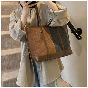 Detail of canvas tote bag with brown leather handles and premium contrast stitching