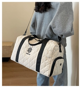 Dettaglio della borsa da viaggio trapuntata bianca con manici neri e logo