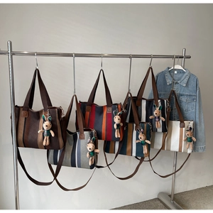 Detail view of colorful striped canvas tote bags with cute bunny pendants and shoulder straps