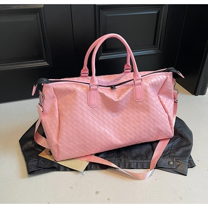 Detail of pink woven leather travel bag showing fine texture and sturdy handles