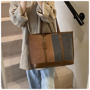 Detail view of large tote bag with color-block texture and brown leather trim on a model
