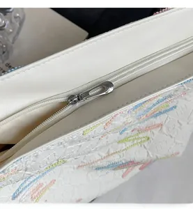 Detail of smooth metal zipper and colorful embroidered texture on white tote bag