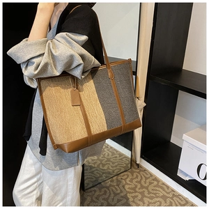 Close-up of contrast stitching canvas tote bag with brown leather handles and tag