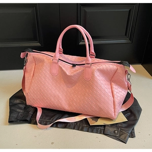 Detail of pink woven leather travel bag with metal zippers and sturdy handles