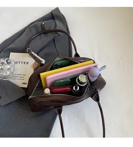 Detail view of the spacious inner compartment of the brown baguette bag holding daily items