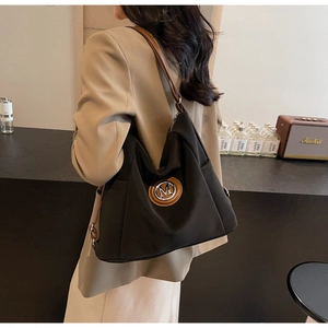 Detail of black tote bag with brown leather shoulder strap shown on a female model