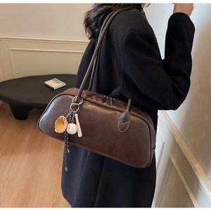 Detail of dark brown leather baguette bag with baseball charms and silver zipper