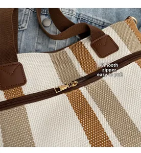 Detail of smooth gold zipper closure on striped canvas tote bag with brown straps