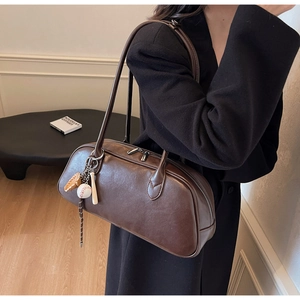 Detail view of deep brown baguette bag with silver zippers and sporty pendant