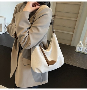 Close-up of white lychee textured crescent tote bag with chain strap and leather tag