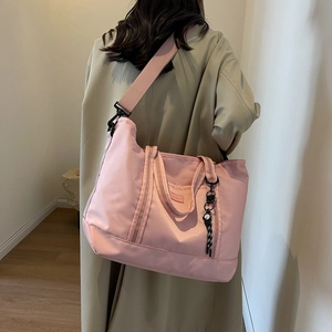 Pink large capacity travel tote bag with crossbody strap shown on a model in trench coat