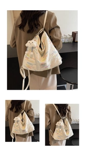 Detail of white quilted tote bag featuring colorful embroidery and plush cloud charm