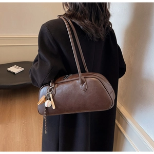 Detail of dark brown leather shoulder bag with vintage baseball pendant accessories