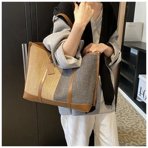 Detailed shot of large tote bag with canvas patchwork and brown faux leather handles