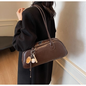 Close-up of a vintage dark brown leather shoulder bag with a unique baseball pendant detail