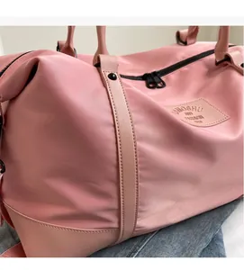 Detail of pink travel duffel bag showing smooth nylon fabric and leather reinforcement