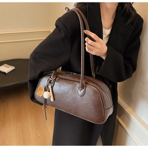 Detail of dark brown leather baguette bag with creative baseball-themed charms and strap