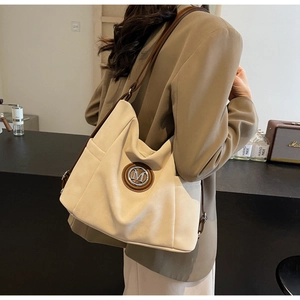 Close-up of suede tote bag with brown leather M logo and vintage shoulder straps